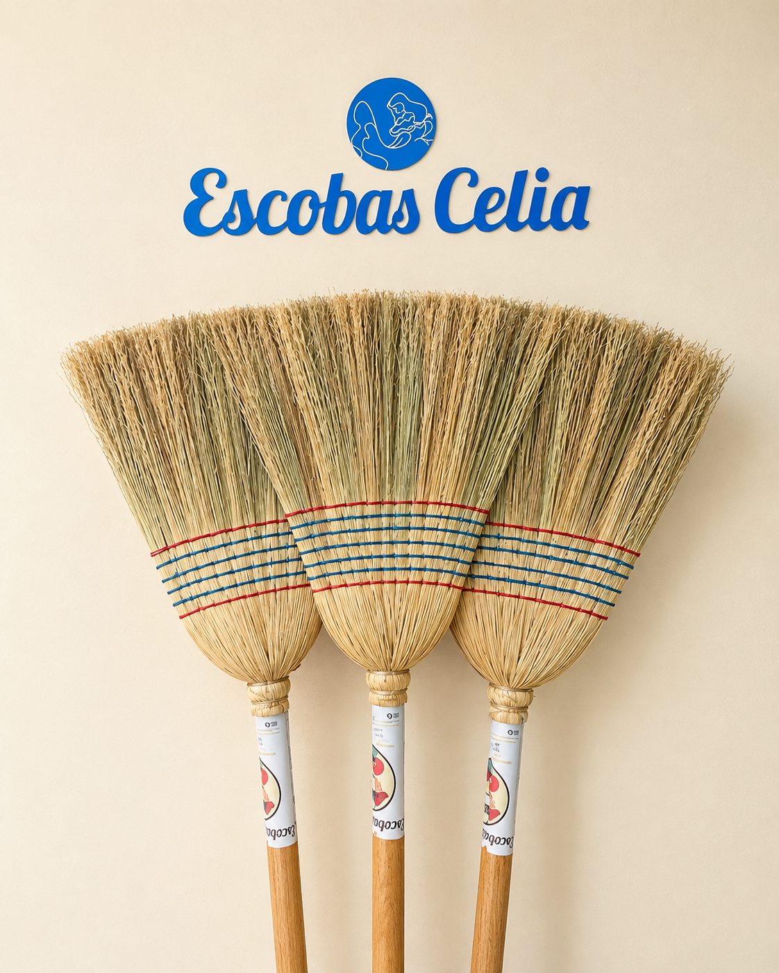 Tres escobas de espiga recargadas en la pared bajo el letrero azul de Escobas Celia